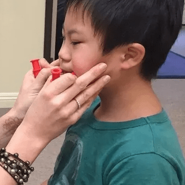 A young boy is brushing his teeth with an adult.