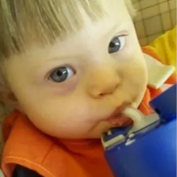 A baby is drinking from a cup.