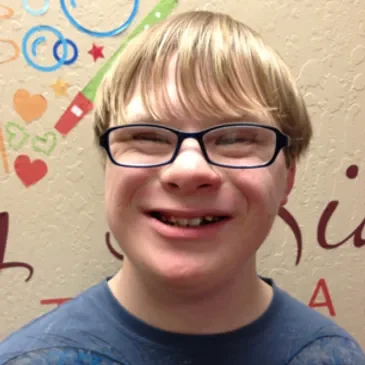 A young boy with glasses smiling for the camera.