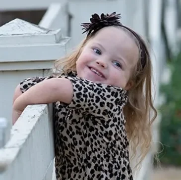 A little girl with long hair and leopard print dress.